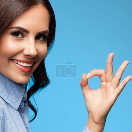Happy showing okay gesture businesswoman, on blue background, with copyspace. Advertising concept. 