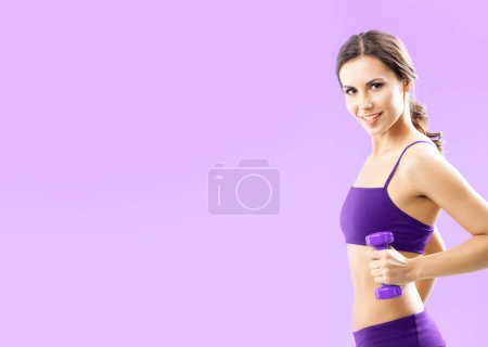 Téléchargez les photos : Jeune femme en tenue de fitness exercice avec haltère, avec copyspace pour certains texte, publicité ou slogan, sur fond rose - en image libre de droit