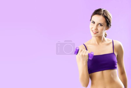 Photo for Young woman in fitness wear exercising with dumbbell, with copyspace for some text, advertising or slogan, against pink background - Royalty Free Image