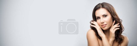 Photo for Portrait of beautiful young woman with long curly hair, over grey background - Royalty Free Image