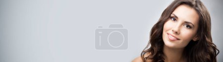 Photo for Portrait of beautiful young happy smiling woman with long curly hair, over grey background - Royalty Free Image