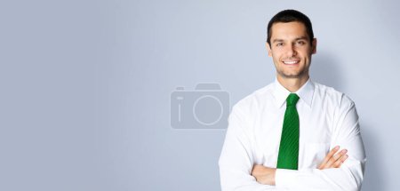 Téléchargez les photos : Portrait d'un homme d'affaires souriant et confiant en cravate verte, les bras croisés, espace de copie vide pour du texte, de la publicité ou un slogan, debout sur fond gris - en image libre de droit