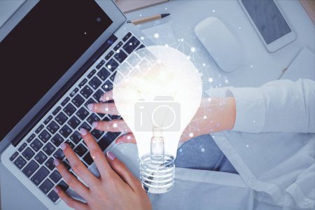 Photo for Double exposure of woman hands working on computer and light bulb hologram drawing. Top View. Idea concept. - Royalty Free Image
