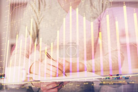 Photo for Hand taking notes in notepad. Forex chart holograms in front. Concept of research. Double exposure - Royalty Free Image
