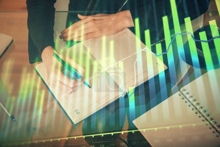 Photo for Forex chart hologram on hand taking notes background. Concept of analysis. Multi exposure - Royalty Free Image