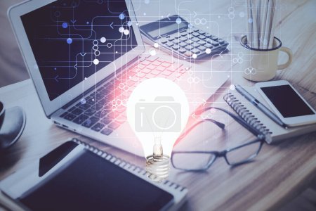 Photo for Computer on desktop in office with bulb icon hologram. Double exposure. Concept of idea. - Royalty Free Image