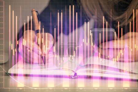 Foto de Doble exposición de las manos de mujer de negocios escribiendo en el dibujo del holograma de la computadora y del gráfico de la divisa. Concepto de análisis financiero. - Imagen libre de derechos