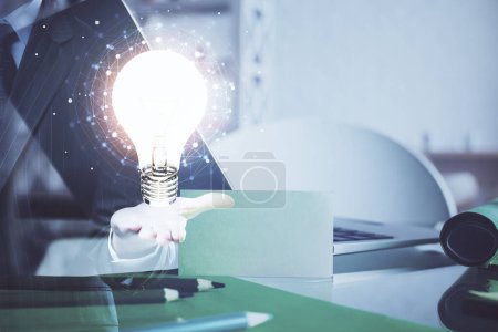 Photo for Computer on desktop in office with bulb icon hologram. Multi exposure. Concept of idea. - Royalty Free Image