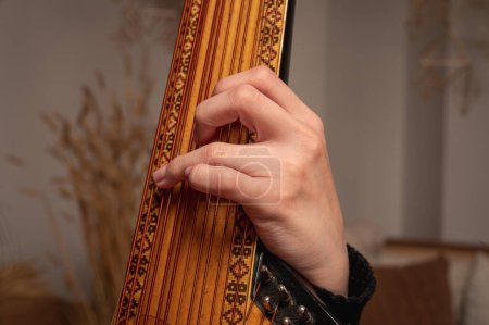 Photo for Young girl plays ukrainian folk instrument, bandura, hands and strings close up - Royalty Free Image