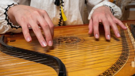Photo for Young girl plays ukrainian folk instrument, bandura, hands and strings close up - Royalty Free Image