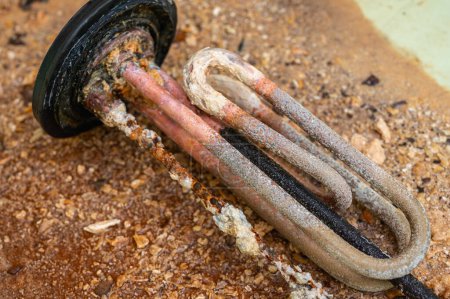 Heizelement eines elektrischen Warmwasserbereiters mit einer rostigen Anode und einem Rohr, das mit einer Schuppe bedeckt ist, einem beschädigten Teil. Wartung und Reparatur.