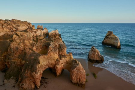 Amazing view of the limestone rocks on secluded beach, Praia dos Tres Irmaos, at sunset. Alvor village, Portugal