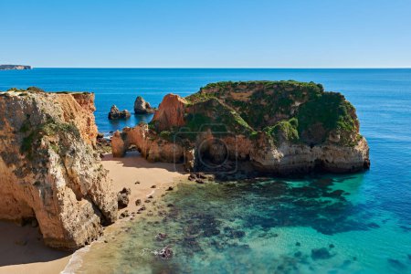 Téléchargez les photos : Un îlot calcaire avec une grotte et une plage isolée entre Portimao et Alvor. Vacances parfaites à la plage dans la région de l'Algarve, Portugal - en image libre de droit