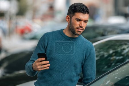 Photo for Man with mobile phone at dealership looking at cars to buy - Royalty Free Image