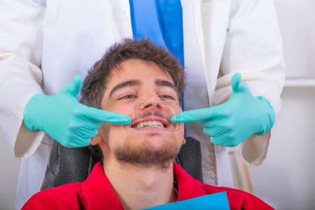 Téléchargez les photos : Dentist showing with hands the mouth and smile of the patient - en image libre de droit
