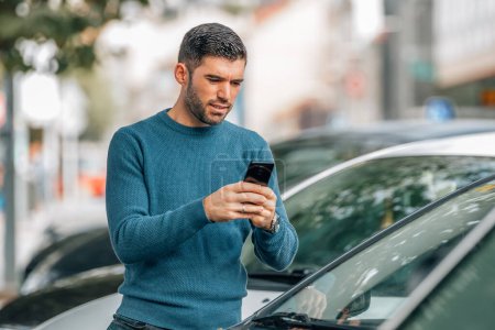 Photo for Man with mobile phone at dealership looking at cars to buy - Royalty Free Image