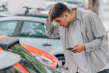 Photo for Young man on the street looking at cars with mobile phone - Royalty Free Image