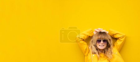 Téléchargez les photos : Femme adulte souriante détendue dans la rue avec mur jaune - en image libre de droit