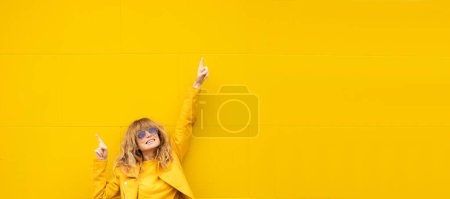 Téléchargez les photos : Femme d'âge moyen sur le mur jaune avec bras tendu de bonheur - en image libre de droit