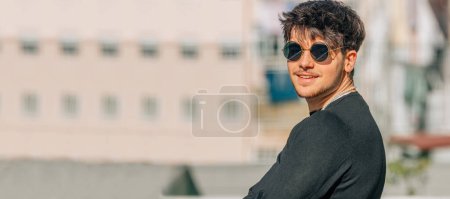 Téléchargez les photos : Portrait de jeune homme avec des lunettes de soleil dans la rue - en image libre de droit