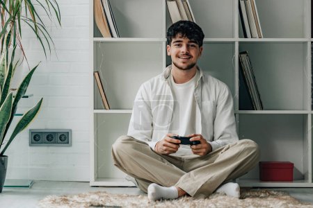 Téléchargez les photos : Jeune homme à la maison avec joystick jouer jeu vidéo - en image libre de droit
