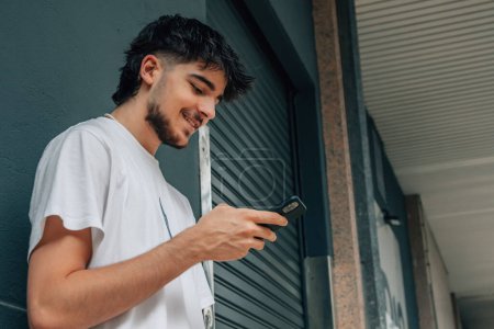 Téléchargez les photos : Jeune homme dans la rue regardant le téléphone mobile - en image libre de droit