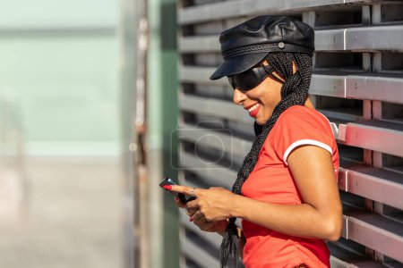 Téléchargez les photos : Fille urbaine dans les lunettes de soleil dans la rue avec téléphone mobile - en image libre de droit