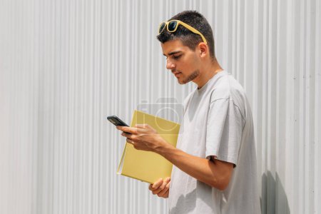 student with books looking at mobile phone