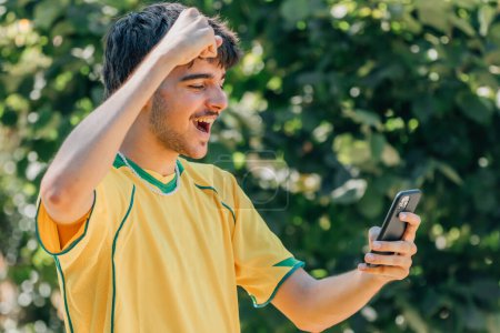 smiling young man watching the game or video on the mobile phone, sport