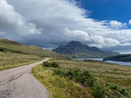 Foto de En el camino a lo largo del Loch Lurgainn, Escocia. Es un gran lago profundo situado al norte a lo largo de la costa oeste de Ullapool, Escocia. Desde la carretera que corre a lo largo del lado del lago, se puede obtener impresionantes vistas de Stac Pollaidh. - Imagen libre de derechos