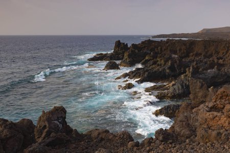 Los Hervideros,rugged volcanic coastline known for waves crashing into sea caves & picturesque views.
