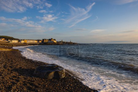 Evening tide on the beach in Aberystwyth at sunset. It is a seaside resort with a long promenade and is situated on the Welsh coast.