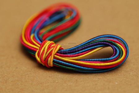Foto de Un paquete vibrante de cordones elásticos de colores atados entre sí, cuidadosamente dispuestos sobre un fondo marrón. - Imagen libre de derechos