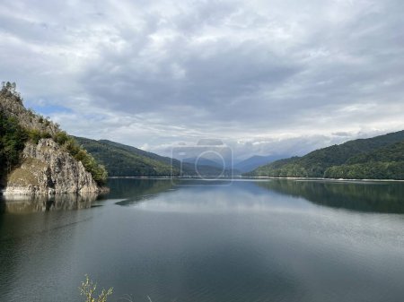 Téléchargez les photos : Lac Vidraru près du barrage, Transfagarasan route, Roumanie. Vue panoramique collines verdoyantes, rochers, nuages paysage - en image libre de droit