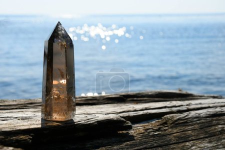 Foto de Una imagen de una torre de cristal de cuarzo ahumado alto con el océano azul brillante detrás de él. - Imagen libre de derechos