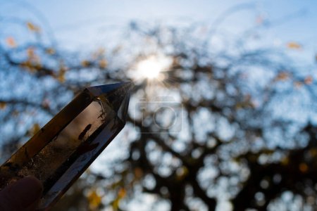 Foto de Una imagen de cerca de una torre de cristal de cuarzo ahumado que se sostiene contra la luz del sol de la tarde. - Imagen libre de derechos
