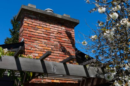 Téléchargez les photos : Une image d'une grande cheminée en brique rouge contre un ciel bleu vif. - en image libre de droit