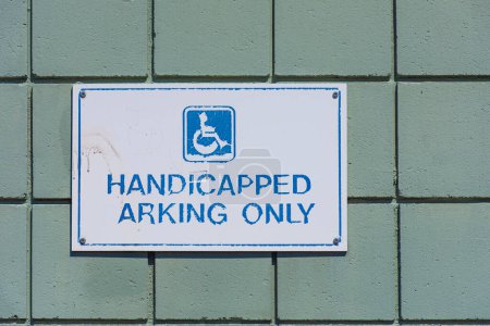 Das Bild eines sehr alten Behindertenparkschildes, das verblasst und abblättert. 