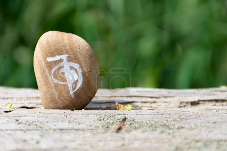 A close up image of a spiritual healing symbol painted on a beige rock.