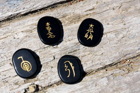 A top view image of several healing reiki symbols written on black tourmaline crystals. 