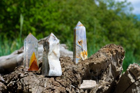 An image of three healing crystal towers standing on the edge of a driftwood log. 