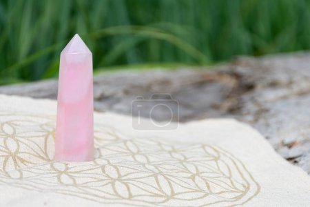 Ein Bild eines hohen Rosenquarzkristallturms auf einem Kristallgittertuch mit der Blume des Lebens heilige Geometrie. 