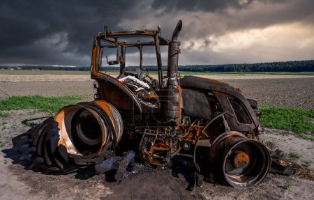 Téléchargez les photos : Tracteur entièrement détruit brûlé sur un champ - en image libre de droit