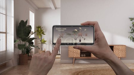 Foto de Remote home control system on a digital smart phone tablet. Device with app icons. Interior of scandinavian living room with chest of drawers, architecture design - Imagen libre de derechos