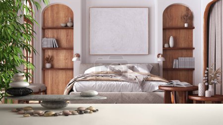 White table shelf with pebble balance and 3d letters making the word feng shui over japandi bedroom with sofa and wooden furniture, zen concept interior design
