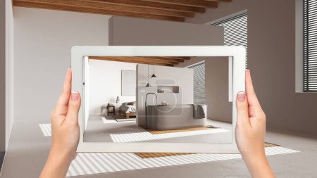 Augmented reality concept. Hand holding tablet with AR application used to simulate furniture and design products in empty wooden interior, japandi minimal bedroom and bathroom
