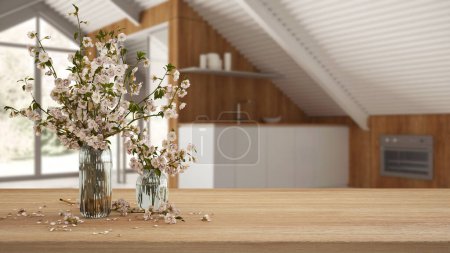 Téléchargez les photos : Table, bureau ou étagère en bois avec des branches de fleurs de cerisier dans un vase en verre sur la mezzanine de mansarde cuisine blanche, concept de design intérieur minimal - en image libre de droit