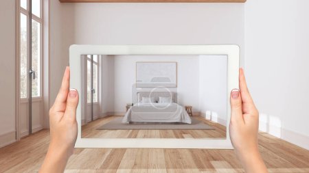 Téléchargez les photos : Concept de réalité augmentée. Tablette à main avec application AR utilisée pour simuler des meubles et des produits de design dans un intérieur en bois vide, chambre minimale japandi - en image libre de droit