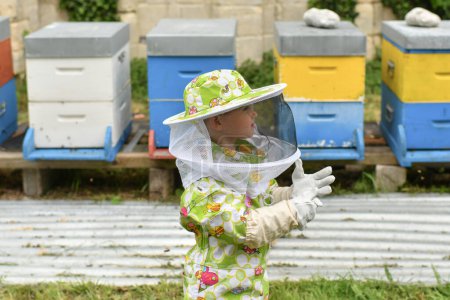 Téléchargez les photos : Un apiculteur enfant en rucher en costume de protection - en image libre de droit