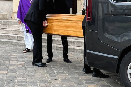 Photo for Funeral service loading the coffin into the hearse - Royalty Free Image